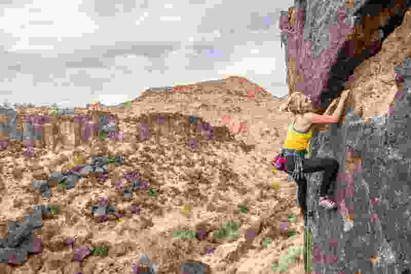 Woman Climbing a black tinted cliff in Black Rocks St George Utah